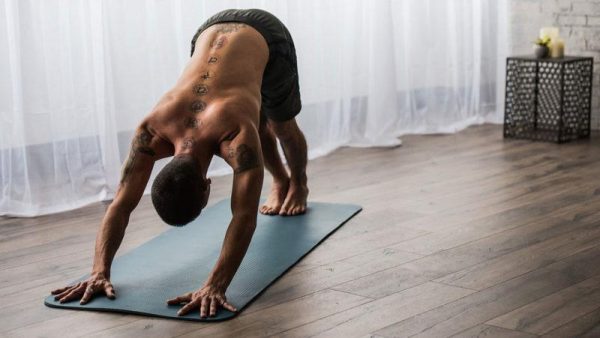 a man with tattoos stretching on a yoga mat