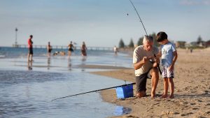 a father teaching his son to fish at the beach