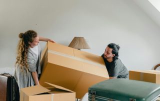 man and woman holding a large moving box as they're packing for a house move