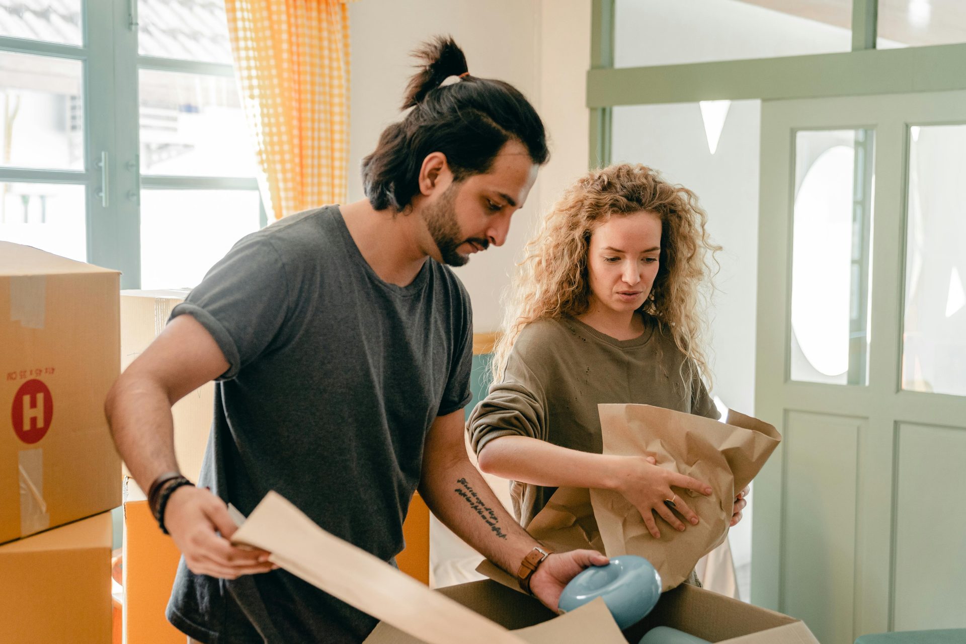 man and woman packing belonging into a moving box during the house buying process